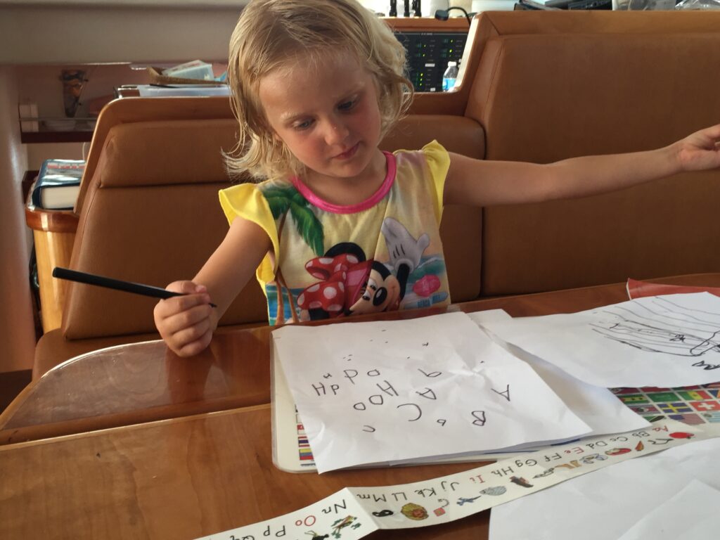 Family life on a sailboat: Karen learning to print the alphabet.