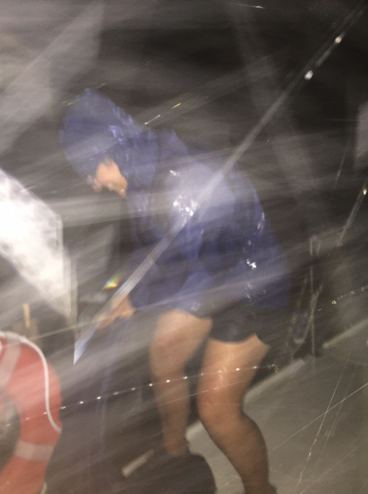 Lorraine taking in the laundry in the rain on SV Aphrodite, a St Francis 50 catamaran.