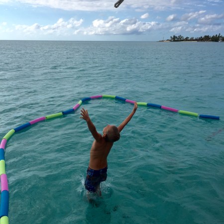 Our son Paul jumping into the sea in the Bahamas with the safety of our DIY swim enclosure.