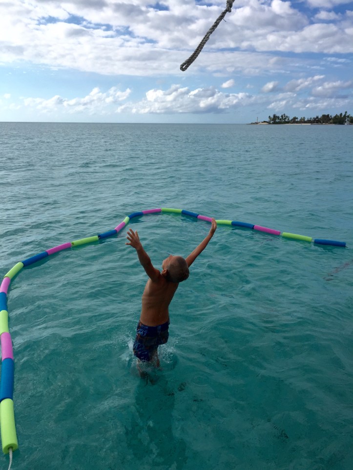 Our son Paul jumping into the sea in the Bahamas with the safety of our DIY swim enclosure.