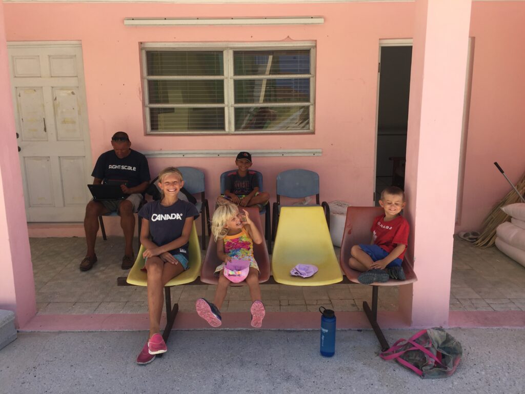 Ragged Islands Bahamas: Escher family of SV Aphrodite outside the clinic in Duncan Town as of 2016. Yet, this clinic was damaged by a hurricane, which we saw in 2019
