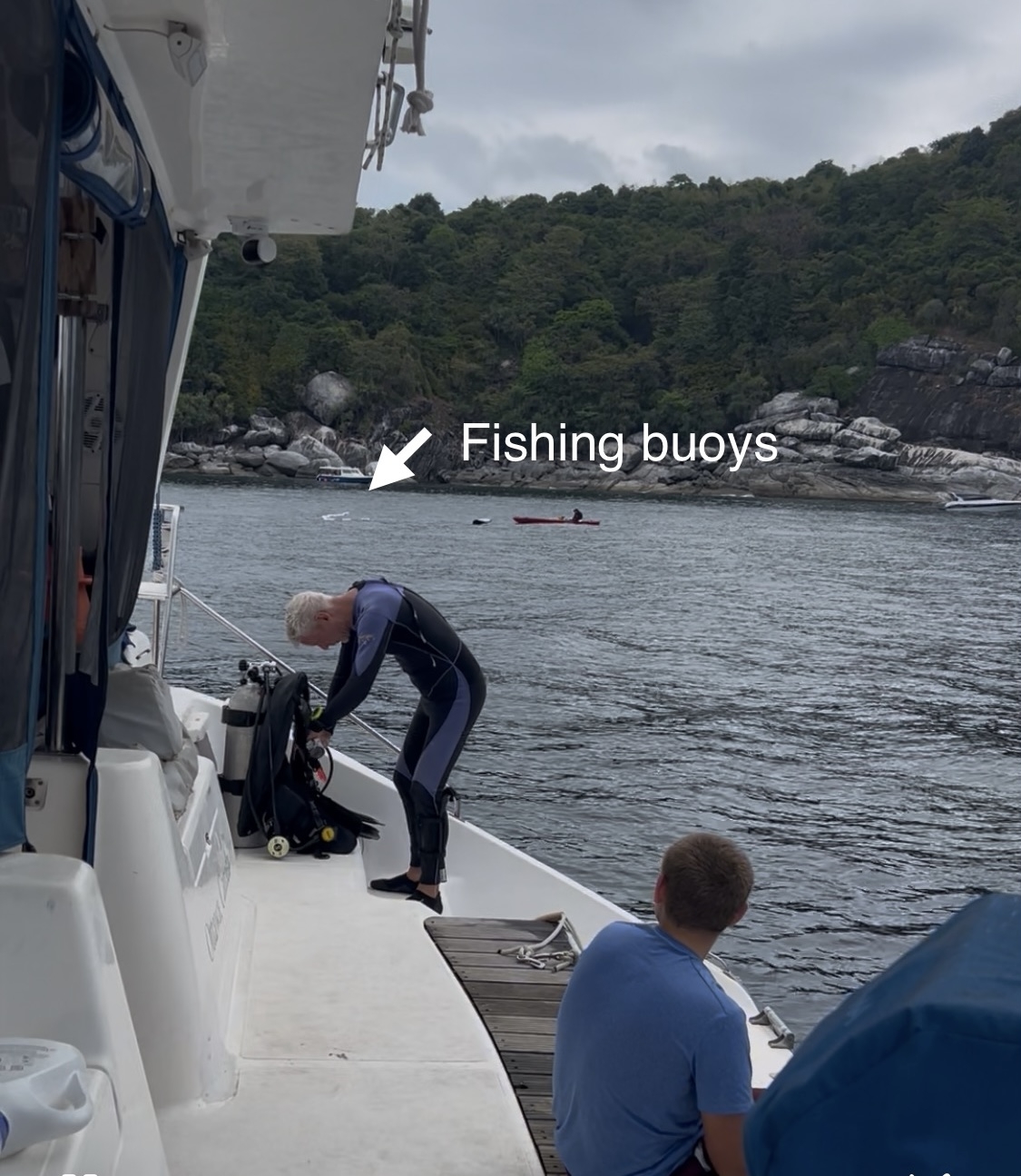 Diver Daves prepares his gear as Henry looks on. Lorraine in on a kayak.