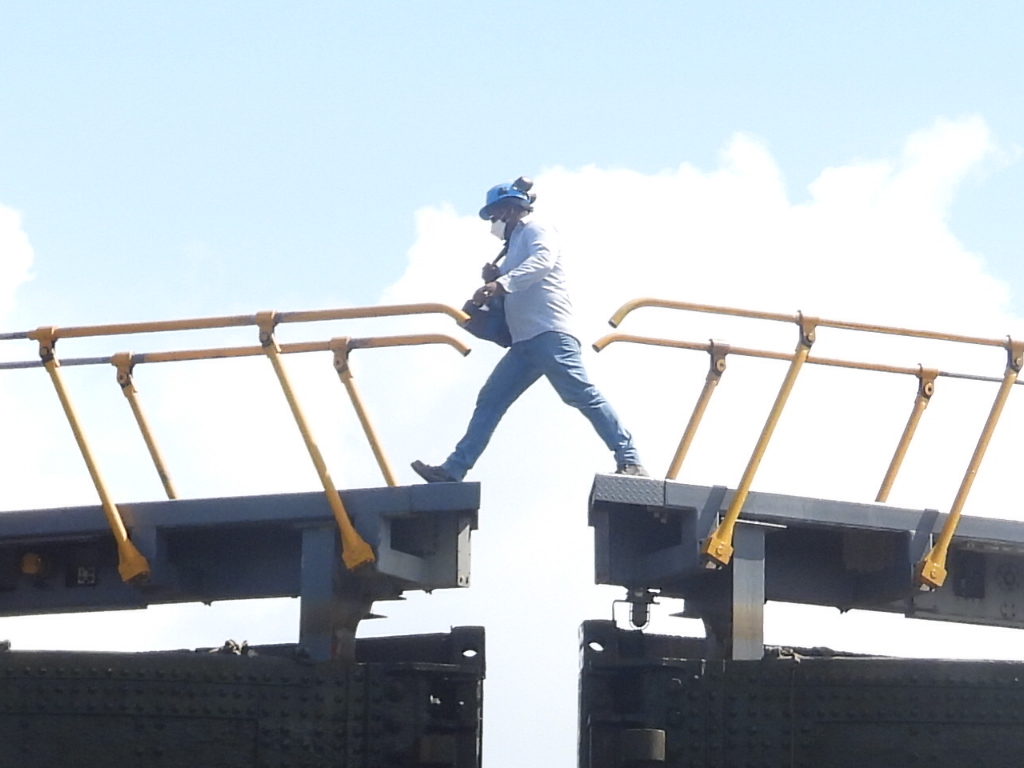 A well timed photo shows a Panama Canal worker walking between the locks of the Panama Canal.