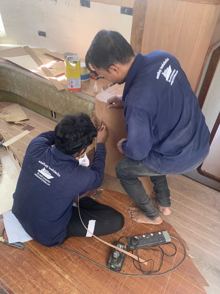 Eastbay Foreman, Rashid, and another woodworker from Eastbay apply new cherry veneer to a cupboard in our saloon.