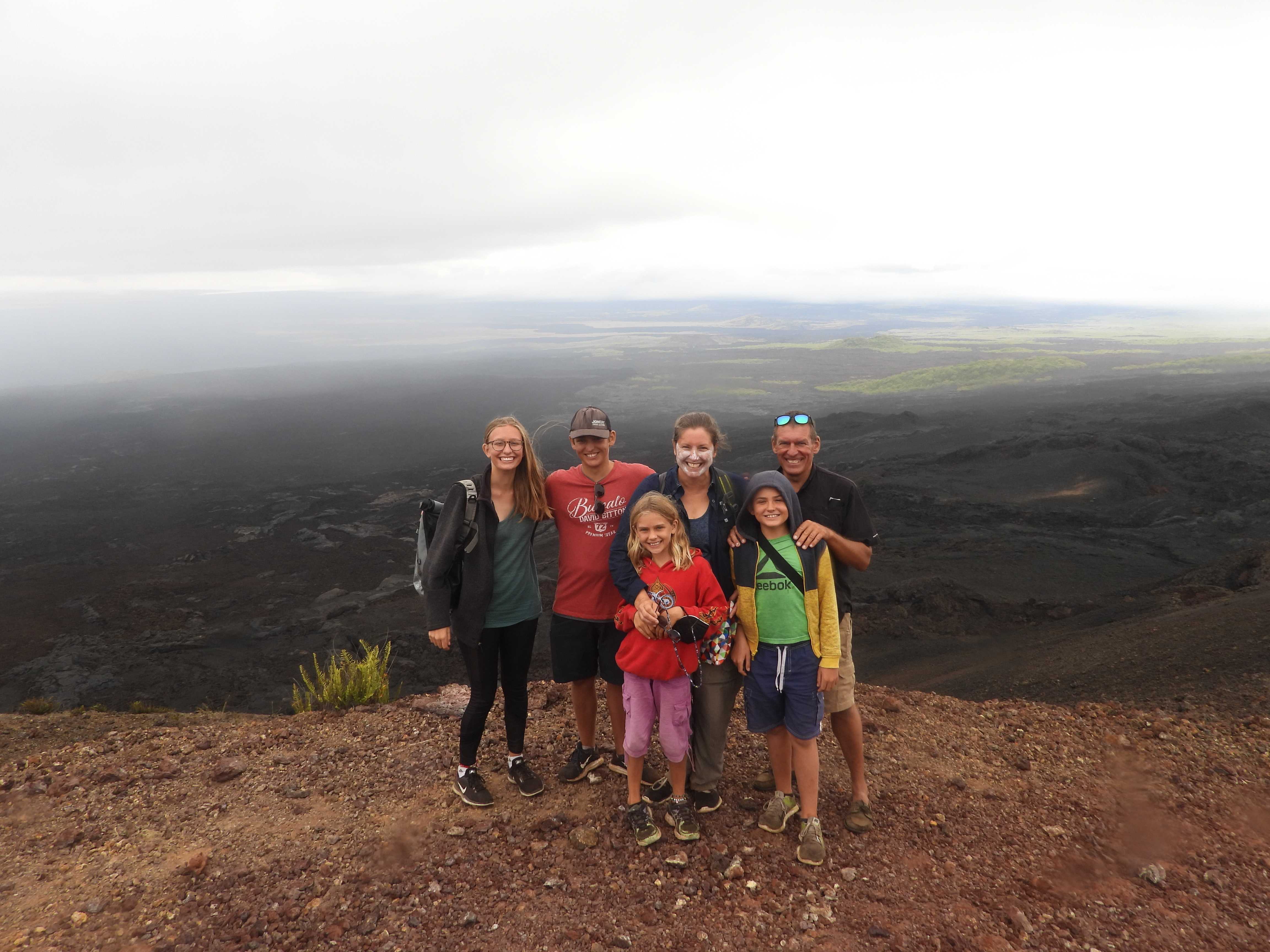Escher family on Sierra Negra Volcano hike in the Galápagos with lava fields in background.