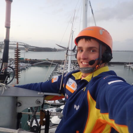 Paul at the top of the mast in Auckland, New Zealand, with the Auckland Harbour Bridge behind.