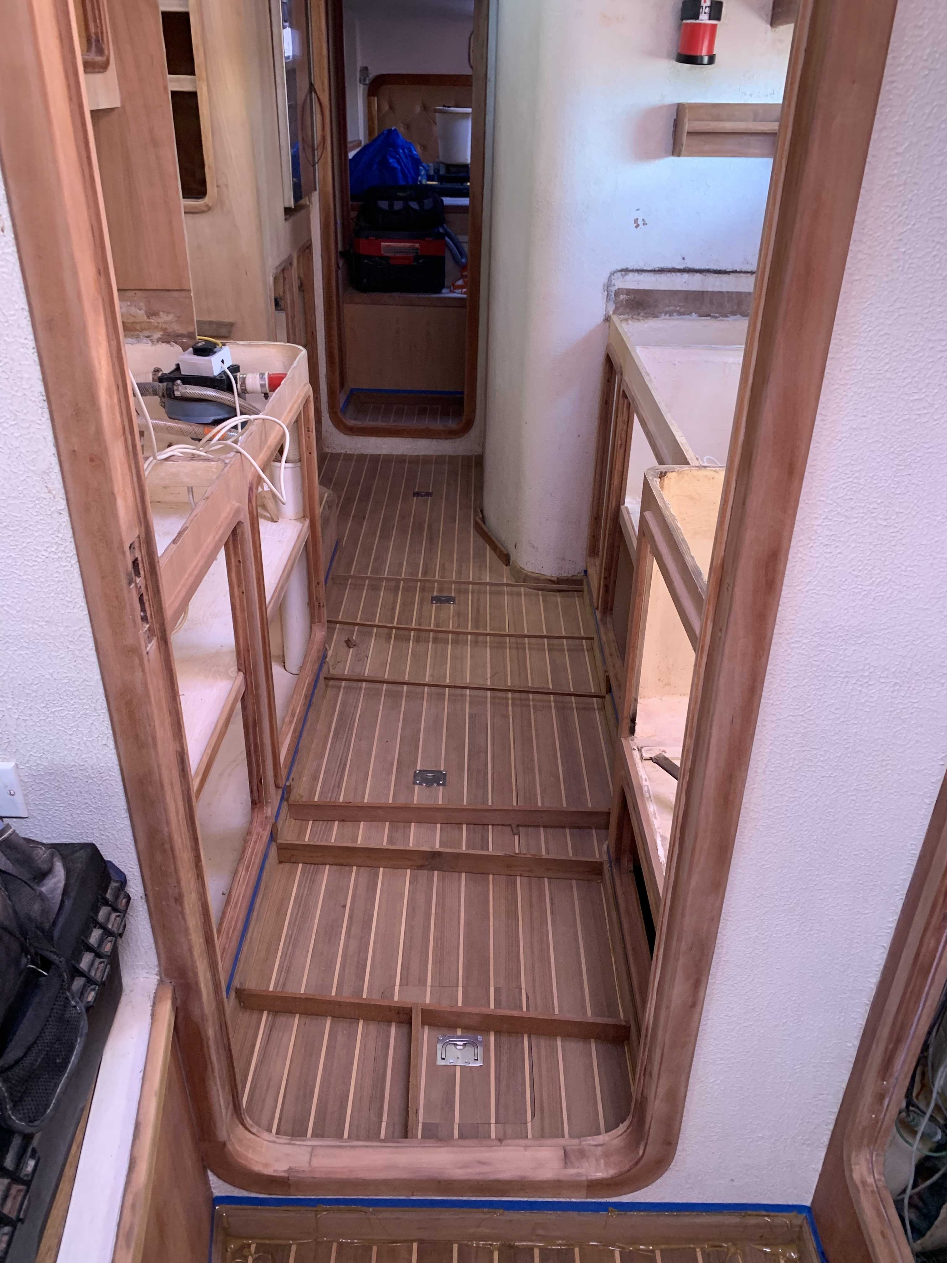 Looking into the galley, Eastbay has replaced the flooring and is gluing the trim, holding it in place with wooden braces across the foor.