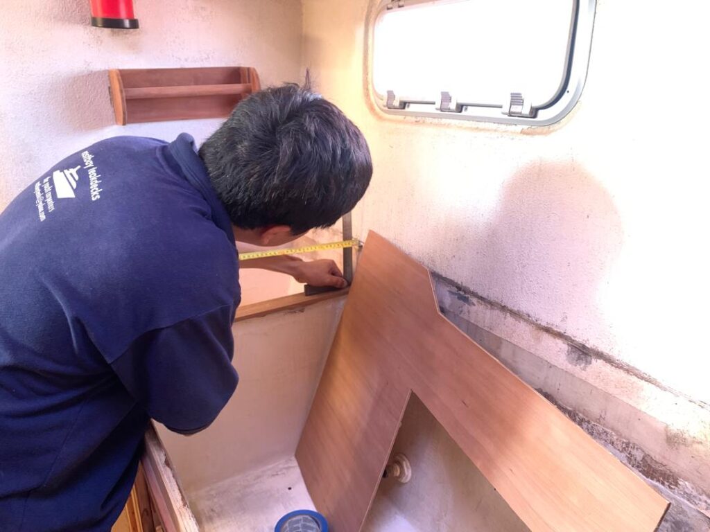 Chin of Eastbay Teakdecks shows a relaxed posture while measuring with accuracy, in this case, the galley-down of SV Aphrodite.