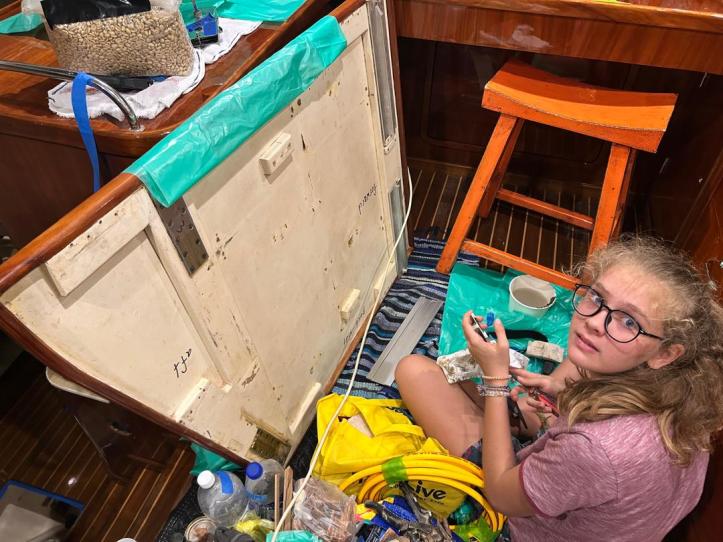 Karen removing the hardware from the underside of the saloon table on our catamaran, SV Aphrodite.